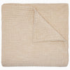 The Vivada Sand Woven Quilt by John Robshaw is shown here neatly folded with one corner turned over, highlighting the luxurious texture and substantial thickness of its cotton fabric—a refined addition to our reversible quilt collection, thoughtfully designed for comfort and style.