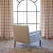 The Square Chair in Marmar Marigold and Natesh Sand by John Robshaw faces a large arched window adorned with patterned curtains, set atop a stone tile floor bathed in natural light. This inviting piece combines stylish design and lasting durability, making it the perfect spot to relax.