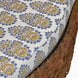 Close-up of a cushion with blue and yellow floral patterns on the Candra Teak Sofa by John Robshaw.