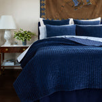 A John Robshaw Velvet Indigo Quilt with a blue velvet comforter and pillows, crafted by Indian artisans. - 30395691696174