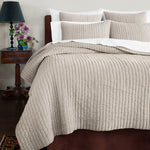 A soft bed with a John Robshaw beige Velvet Sand Quilt and plush pillows. - 30395695235118