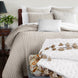 A soft John Robshaw bed with Velvet Sand Quilt pillows adorned with tassels.