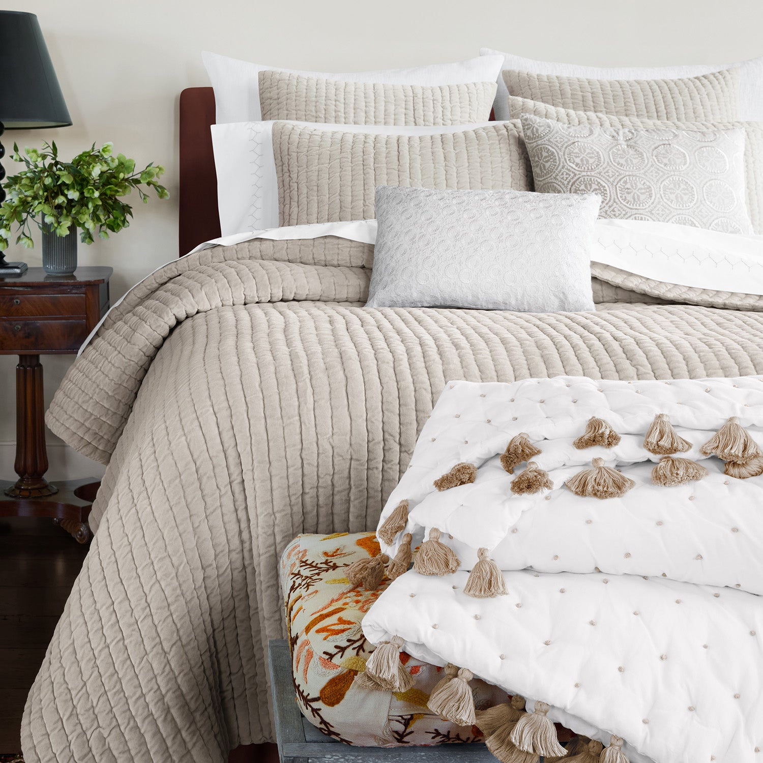 A soft John Robshaw bed with Velvet Sand Quilt pillows adorned with tassels.