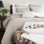 A soft John Robshaw bed with Velvet Sand Quilt pillows adorned with tassels. - 30395695202350