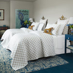 Two beds in a room with a Layla Sand Quilt by John Robshaw on one and cotton voile bedding mix on the other, with a blue rug. - 30403072163886