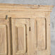 Close-up of the top section of the John Robshaw Capala Teak 2 Part Cabinet, featuring bleached teak panels in a geometric design, set against a gray textured wall.
