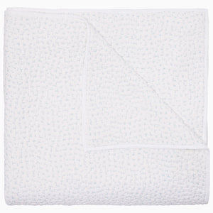 The John Robshaw Organic Hand Stitched Mist Quilt, crafted from soft cotton voile with a subtle woven texture, is shown folded and viewed from above, with one corner partially flipped over.