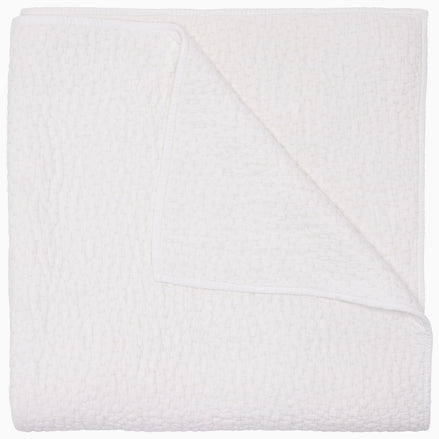 The Organic Hand Stitched White Quilt by John Robshaw features a beautifully textured, white woven design with one corner turned up to reveal its intricate hand stitching on both sides—ideal for layering with organic cotton quilts or other hand-stitched bedding to bring warmth and refined elegance to any bedroom.