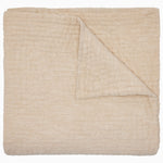 The Vivada Sand Woven Quilt by John Robshaw is shown here neatly folded with one corner turned over, highlighting the luxurious texture and substantial thickness of its cotton fabric—a refined addition to our reversible quilt collection, thoughtfully designed for comfort and style.