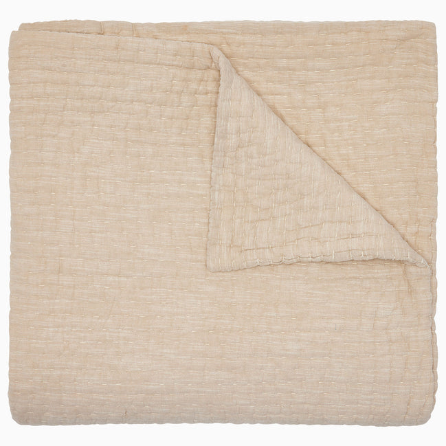 The Vivada Sand Woven Quilt by John Robshaw is shown here neatly folded with one corner turned over, highlighting the luxurious texture and substantial thickness of its cotton fabric—a refined addition to our reversible quilt collection, thoughtfully designed for comfort and style.