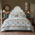 A hand quilted Bipin Tangerine Quilt bed with a blue and orange floral comforter made of pure cotton voile by John Robshaw. - 30784339378222