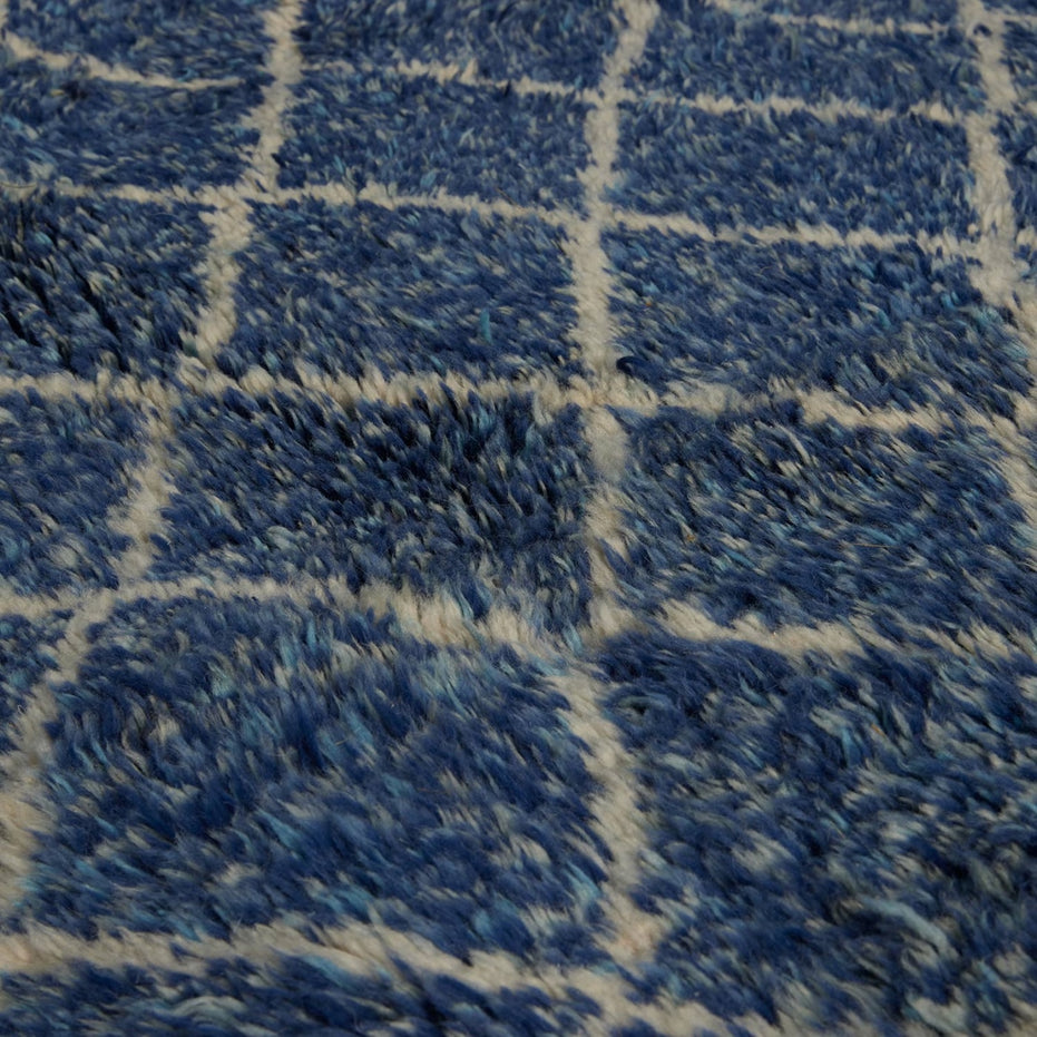 Shaggy blue John Robshaw Blue Village Wool Rug with a white grid pattern.