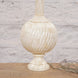 The Shiva Bone Inlay Lamp by John Robshaw sits on a wooden surface, featuring a cream-colored, textured round base and accompanied by a clear electrical cord and plug. Its handcrafted appearance is inspired by classic Mughal ginger jar designs.