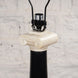 Close-up of the Roshni Bone Inlay Lamp by John Robshaw, featuring a design inspired by a classical column with a black base and a white Ionic capital, evoking the elegance of a Colonial Indian lamp, set against a light-colored textured wall.