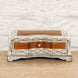 The Harini Bone Inlay Box by John Robshaw is a rectangular handcrafted teak box featuring an intricate floral inlay design, a single small front drawer with a brass knob, and sits gracefully on a wooden surface against a white brick wall—this vintage Indian-inspired piece infuses any space with timeless charm.