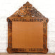 The Ila Bone Inlay Mirror by John Robshaw features an intricate cut-out design with exquisite inlay work, a rectangular base, and a pointed top. This striking hand-carved piece comes equipped with a hanging wire on the back and makes a bold statement when displayed against a white brick wall.