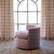 A John Robshaw Round Swivel Chair in Marmar Berry and Aleppo Berry, upholstered in patterned pink performance fabric, sits on a stone floor before a large arched window adorned with matching patterned curtains.
