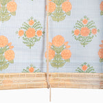 The Bipin Tangerine Chik Blinds by John Robshaw Textiles are handmade bamboo window blinds featuring orange flowers and green leaves against a blue and white striped background, inspired by Indian chik blind styles. - 31884733284398