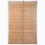 The Lapis Stripe Chik Blinds by John Robshaw Textiles, featuring a handmade bamboo design with a wavy pattern reminiscent of Indian chik blinds, hangs closed and vertically against a plain white background. - 31884734136366