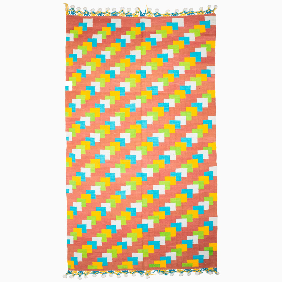 A vibrant beach towel featuring a stylish pattern of triangles, reminiscent of vintage rugs from Punjab's weaving centers, the Left to Right Then Back Again Rug by John Robshaw.