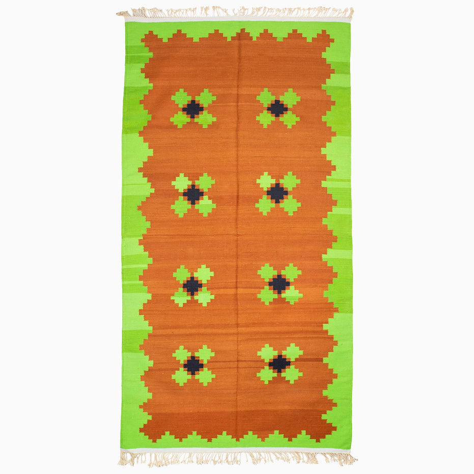 A Lime and Tea Rug in orange and green with a geometric pattern, handcrafted by the John Robshaw weaving center.