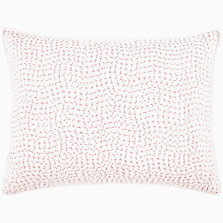 A John Robshaw Organic Hand Stitched Lotus Quilt with a pink and white pillow with dots on an organic cotton voile coverlet.