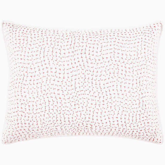 A John Robshaw Organic Hand Stitched Lotus Quilt with a pink and white pillow with dots on an organic cotton voile coverlet.