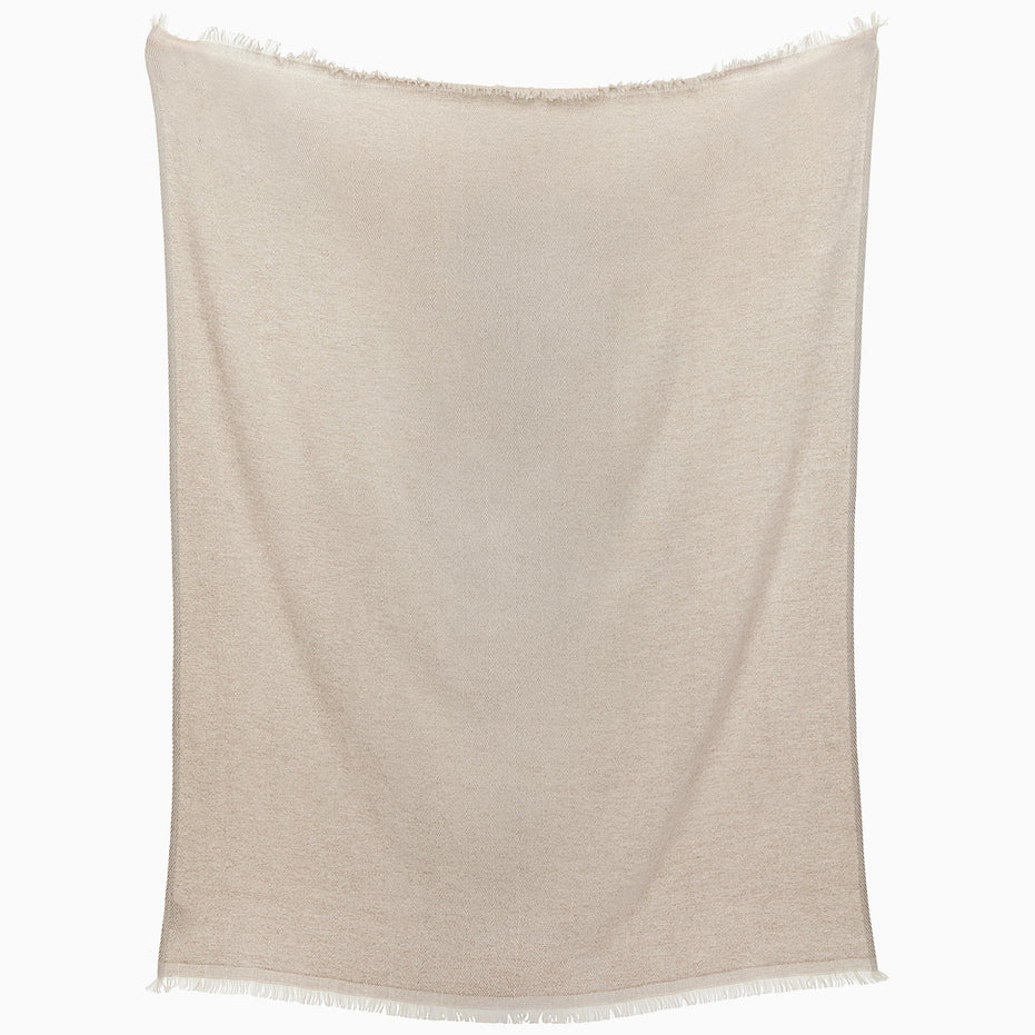 The Lavanya Sand Throw by John Robshaw, a beige herringbone blanket with fringed edges, hangs flat against a white background.