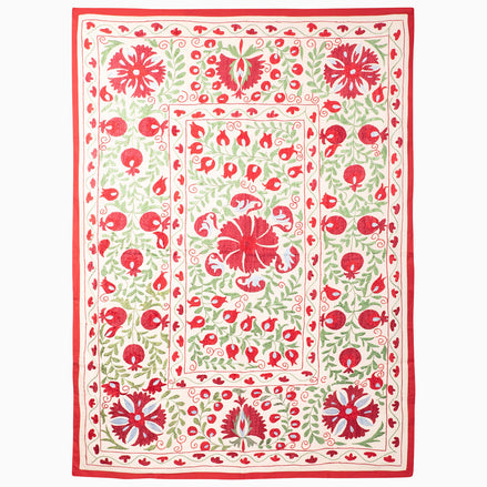 Crimson Bloom Suzani Blanket: an off-white rectangular vintage textile featuring red and green floral and pomegranate embroidery, framed by a red border.