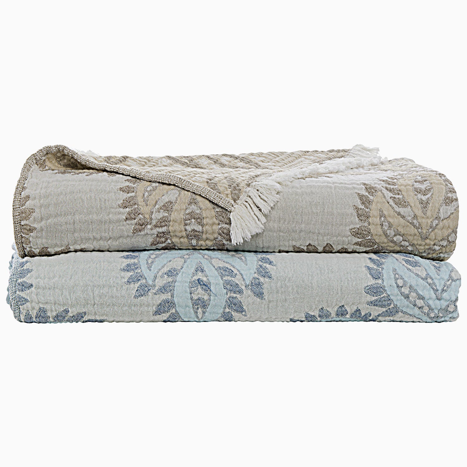 Two folded patterned blankets, one brown and one blue, stacked on top of each other. The top blanket, the Dasati Sand Throw from John Robshaw, is crafted from stonewashed cotton and also features fringe detailing.