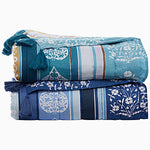 Two folded Malvika Lapis Throws by John Robshaw, featuring blue quilts adorned with white floral and geometric patterns and accented with corner tassels, are stacked together. Crafted entirely from 100% cotton voile, these hand-printed throws add a touch of elegance to any room. - 31274109108270