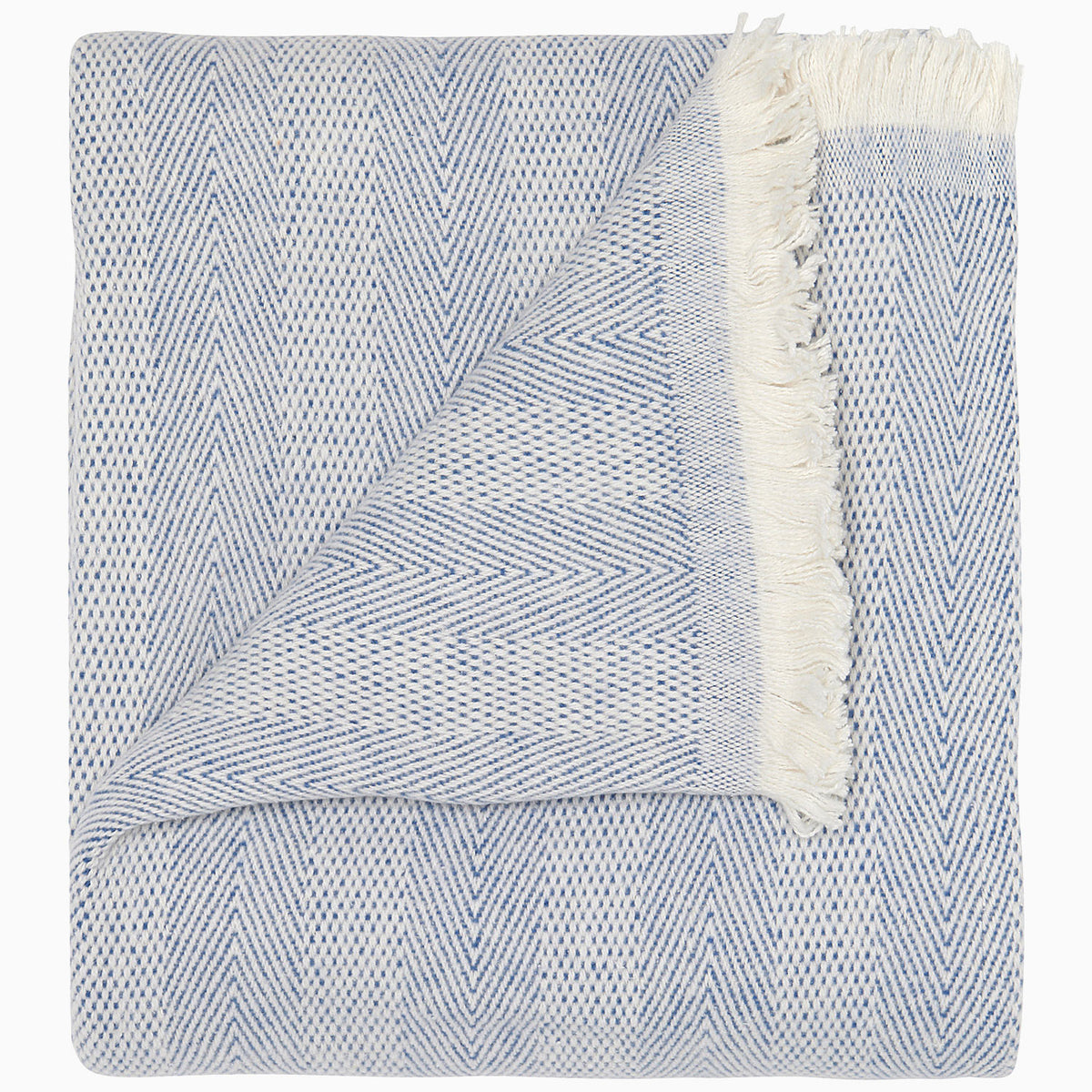 Lavanya Indigo Throw by John Robshaw features a folded herringbone weave, indigo cotton with fringe on one edge, and a flipped corner to highlight its texture.