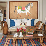 A vintage living room adorned with hand-painted Indian treasures, including a John Robshaw White Horse with Link Saddle Tapestry on the wall. - 30720448659502