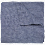 A Vivada Indigo Woven Quilt by John Robshaw folded on top of itself.