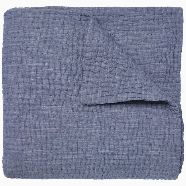A Vivada Indigo Woven Quilt by John Robshaw folded on top of itself.