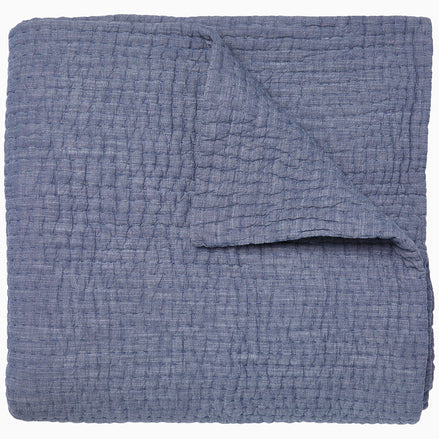 A Vivada Indigo Woven Quilt by John Robshaw folded on top of itself.