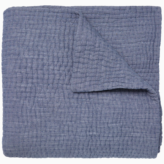 A Vivada Indigo Woven Quilt by John Robshaw folded on top of itself.