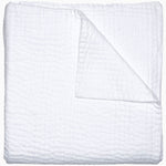 A Vivada White Woven Quilt by John Robshaw folded on top of a white surface with hand stitching.
