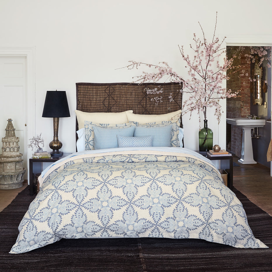 A bedroom with a blue and white comforter featuring a John Robshaw Cinde Light Indigo Organic Sheet Set made from 100% cotton percale.