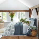 A beautifully designed blue and white bedroom with wooden beams, featuring machine washable John Robshaw Sag Harbor Peacock Organic Sheets in a stylish block print pattern. - 28198852100142