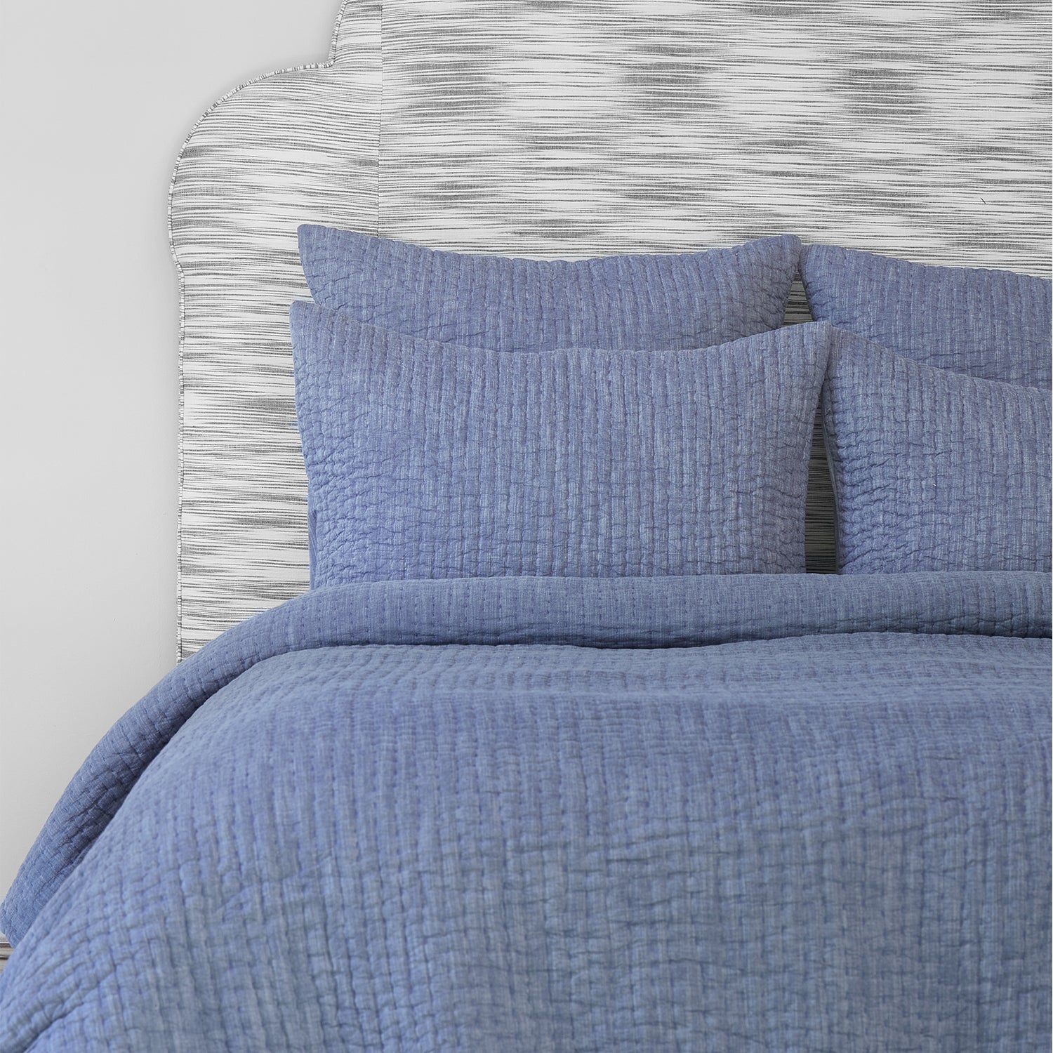 A bed with a John Robshaw Vivada Indigo Woven Quilt made of cotton chambray.