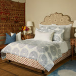 A vintage woodblock print-inspired bed with a handcrafted look, adorned with a blue and white comforter featuring an exquisite John Robshaw Lapis Quilt pattern. - 29588933607470