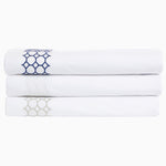 A stack of Sana Light Gray Organic Sheet Sets by John Robshaw with an embroidered chain motif. - 28739479339054