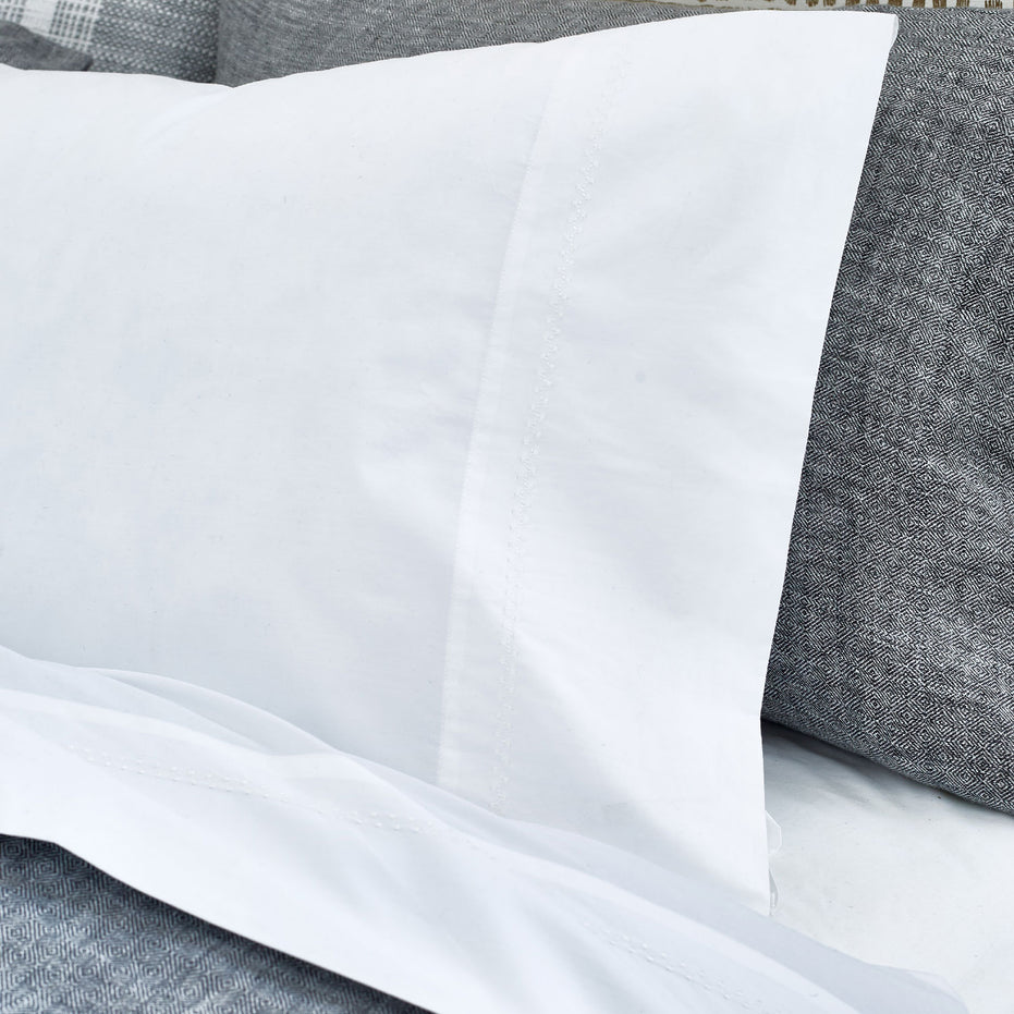 An image of a bed with John Robshaw's Anketi White Organic Sheet Set and pillows.