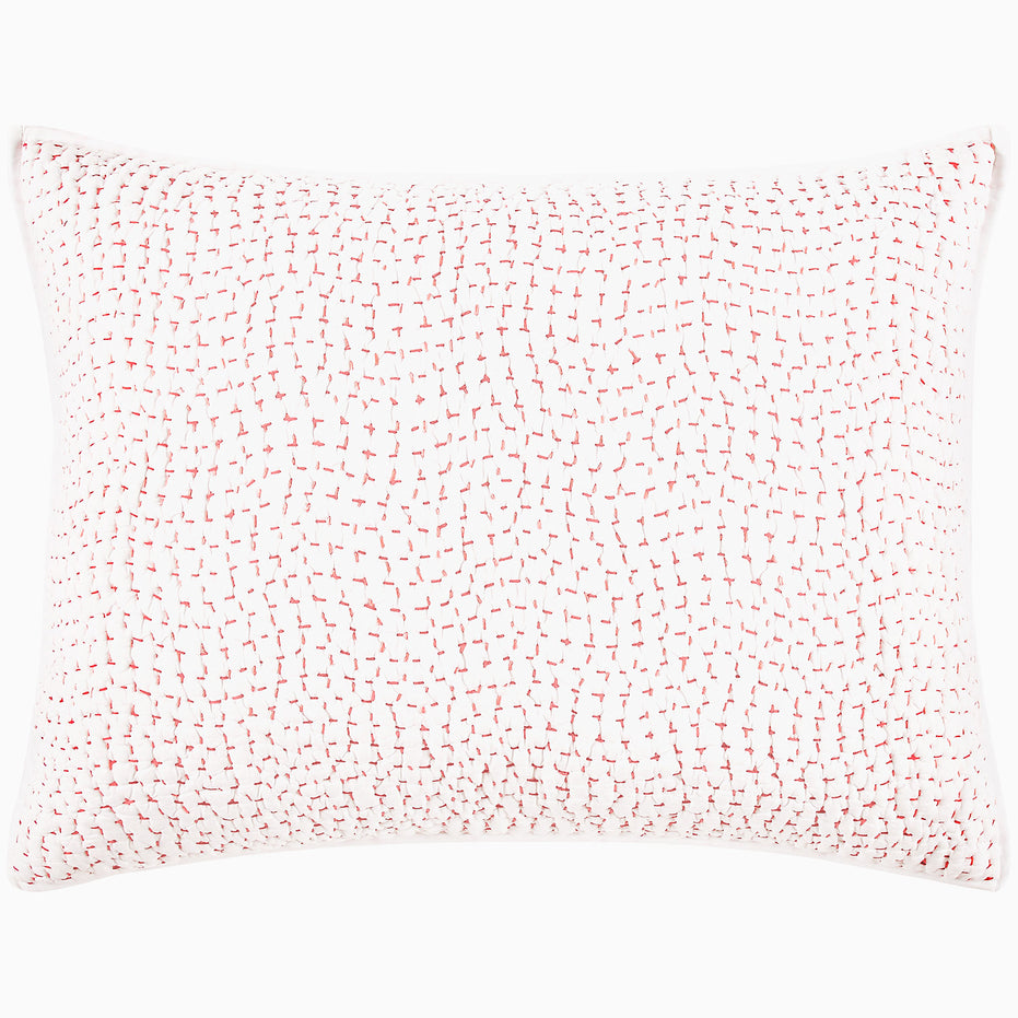 A John Robshaw Organic Hand Stitched Lotus Quilt with a pink and white pillow with dots on an organic cotton voile coverlet.