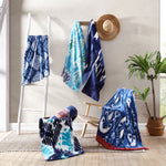 A group of John Robshaw's Sashpura Indigo Beach Towels hanging on a ladder in a room, handcrafted by Uzbekistan's expert weavers. - 29274370801710
