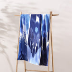A Malda Indigo Beach Towel, hand-woven by Uzbekistan's skilled artisans, hanging on a wooden rack. - 29274360971310