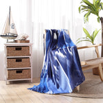 A blue and white Malda Indigo Beach Towel by John Robshaw on a chair in a room, woven by skilled hand weavers using the traditional Ikat technique. - 29274361167918