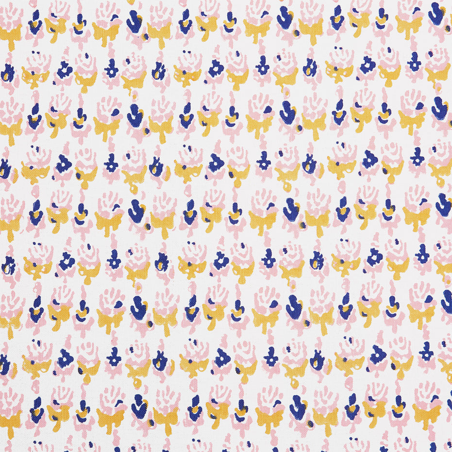 A close up of a Kiki Oyster Fabric hand block printed pink, blue and yellow flower batik by John Robshaw.