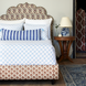 A Layla Azure Quilt bed with a blue and white patterned headboard inspired by Mughal gardens, designed by John Robshaw.